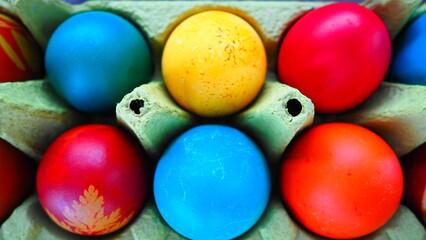 Fototapeta na wymiar Multi-colored eggs painted with gouache and onion peel in a cardboard box close up. Ten boiled eggs. Postcard poster for Easter. Easter holiday. Red, blue, yellow, brown eggs