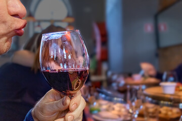 The man stretches his lips to a glass of wine. Alcohol addiction. Funny facial expression.