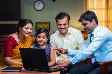 Bank officer explaining about child insurance or loan policy to couple at home - concept of...