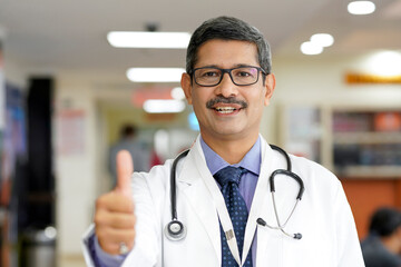 Indian male doctor showing thumps up at hospital.