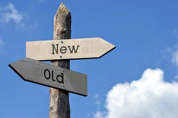 Old or new - wooden signpost with two arrows, sky with clouds