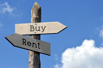 Buy or rent - wooden signpost with two arrows, sky with clouds