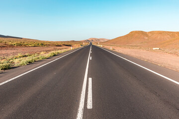 Fototapeta na wymiar Empty road through desert valley in Fuerteventura island, Spain