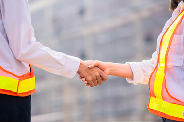 Engineer standing shake hand construction project background