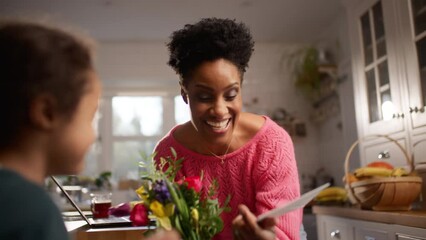 Boy with Down Syndrome giving mother bouquet and card on Mother's Day