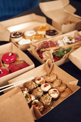 Close up view of table with food on it. Meat, vegetables, sushi, French fries, burger, mushrooms