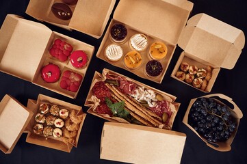 View from the top of table with food on it. Meat, vegetables, sushi, French fries, burger, mushrooms
