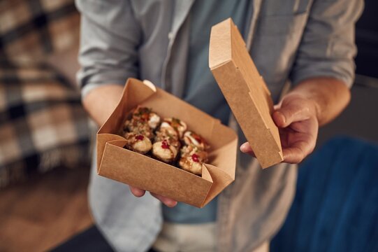 Opening the paper eco box. Man in casual clothes is holding sushi