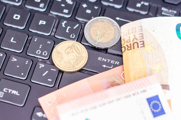 Euro banknotes and coins on a computer keyboard.