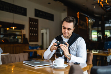 one man use digital mirrorless camera while sit at cafe or restaurant