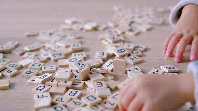 hands close-up, small child 3 years old plays wooden alphabet blocks, makes up words from letters, dyslexia awareness, learning difficulties, human brain development, happy childhood, selective focus