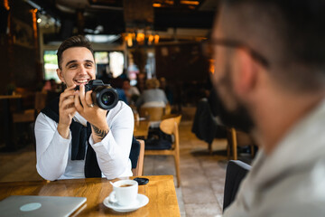 one man use digital mirrorless camera while sit at cafe or restaurant