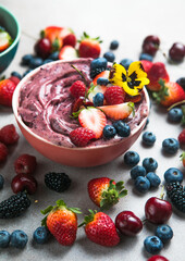 Two summer acai smoothie bowls with strawberries, blueberries,   on gray concrete background. Breakfast bowl with fruit and cereal, close-up, top view, healthy food