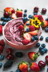 Two summer acai smoothie bowls with strawberries, blueberries,   on gray concrete background. Breakfast bowl with fruit and cereal, close-up, top view, healthy food