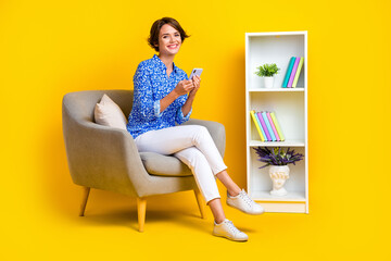 Full length photo of shiny sweet woman dressed blue blouse typing message modern gadget isolated yellow color background