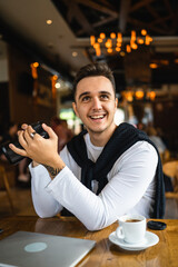 one man use digital mirrorless camera while sit at cafe or restaurant