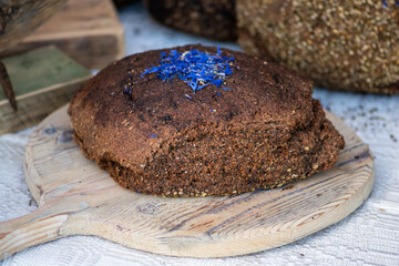 Homemade black rye cereal bread with hemp seeds in a traditional street food market, close up