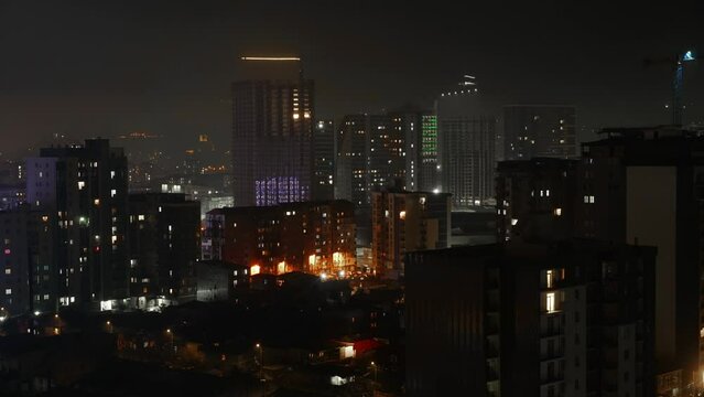 Time lapse night cityscape and high-rise buildings in metropolis city center . Business center of Batumi in Georgia with panoramic views. Public transport Business district against backdrop mountains.