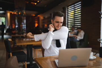 one man sit at the table at restaurant having neck pain or strain