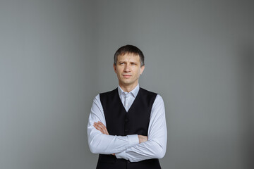 Male portrait in a classic shirt and vest on a gray background