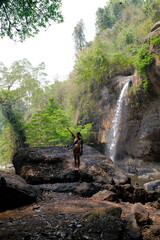A young woman visiting Haew Suwat Waterfall, a natural beauty in a large forest