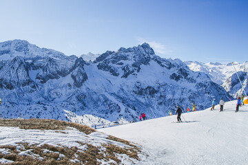 Fototapeta na wymiar A beautiful scenery of the italian Alps with skiing people. Ponte di Legno, Italy.