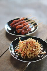 Papaya salad and grilled chicken are on the table