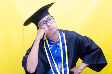 sad Asian man in graduation cap and gown rubbing his tears. student frustration concept. crying asian male student with glasses and graduation gown.