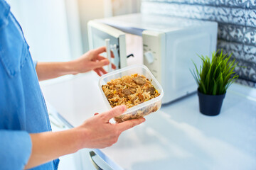 Person heating food using microwave oven