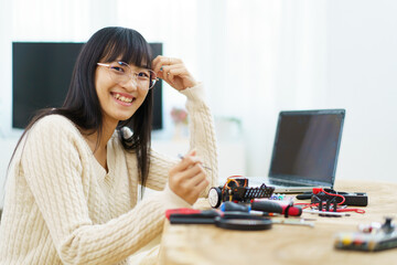 Happy cheerful Asian ethnicity female university student learning about robotic and programing by...