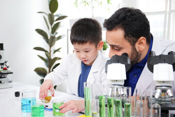 Lovely Asian young boy in lab coat enjoy doing an experiment and studying a science.