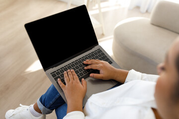 Woman using laptop, mockup, sitting on sofa at home