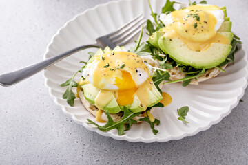 Healthy egg benedict with avocado and arugula