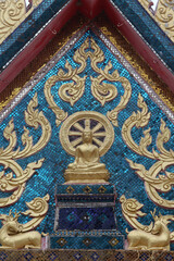Fototapeta na wymiar Sitting Buddha, dharma wheel and deer statues on a Hua Hin temple tympanum. Thailand.