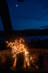 A campfire on Taylor Pond in the Adirondack mountains with a slight illuminatio of the moon