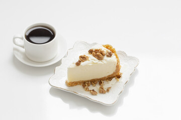 cup of coffee and cheesecake  on white table