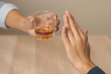 Alcoholism, sad depressed asian young man, male hand holding glass, refuse alcoholic beverage, drink whiskey at night. Treatment of alcohol addiction, having suffered abuse problem alcoholism concept.