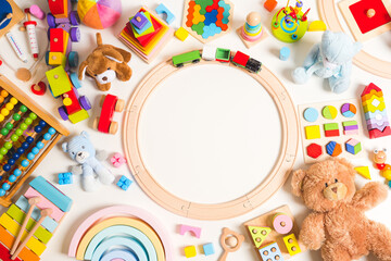 Baby kids toys frame background. Teddy bear, wooden educational, musical, sensory, sorting and stacking toys, wooden train, rainbow, abacus, building blocks on white background. Top view, flat lay