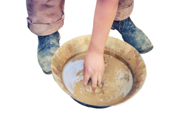 A man washes gold sand in a copper tray, isolated on a white background. Washing of gold in the tray by American pioneers in Klondike