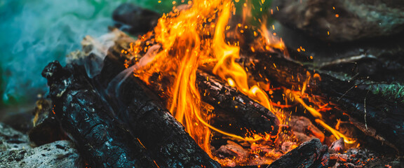 Vivid smoldered firewoods burned in fire close-up. Atmospheric background with orange flame of...