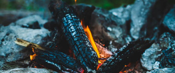 Vivid smoldered firewoods burned in fire close-up. Atmospheric warm background with orange flame of...