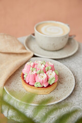 Aesthetic floral french tart with cappuccino cup. Pink floral, surreal flowers cake outside. Desserts using the trend Dreamy Escapism, layers.