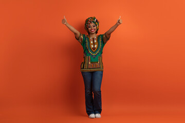 Cool cheerful african woman in national costume showing thumb ups