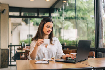 Fototapeta premium Thinking about how to take the business to technological heights. Screenshot of an attractive young businesswoman working in her office holding a cup of coffee