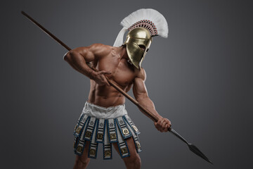 Portrait of strong warrior from antique greece holding spear against grey background.