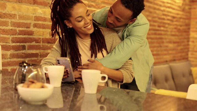 African american couple watching smart phone and having breakfast. Happy couple eating at home