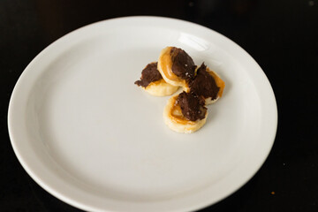 four pieces of frozen banana with peanut butter and melted chocolate with flaky salt on white plate, copy space