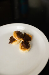 four pieces of frozen banana with peanut butter and melted chocolate and sprinkle of flaky salt on white plate sitting on black countertop