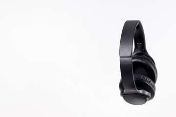 Black headband headphones to listen to music in free time, doing sports or traveling. Close-up on white background