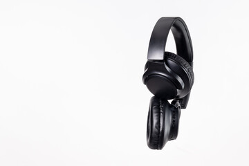 Black headband headphones to listen to music in free time, doing sports or traveling. Close-up on white background